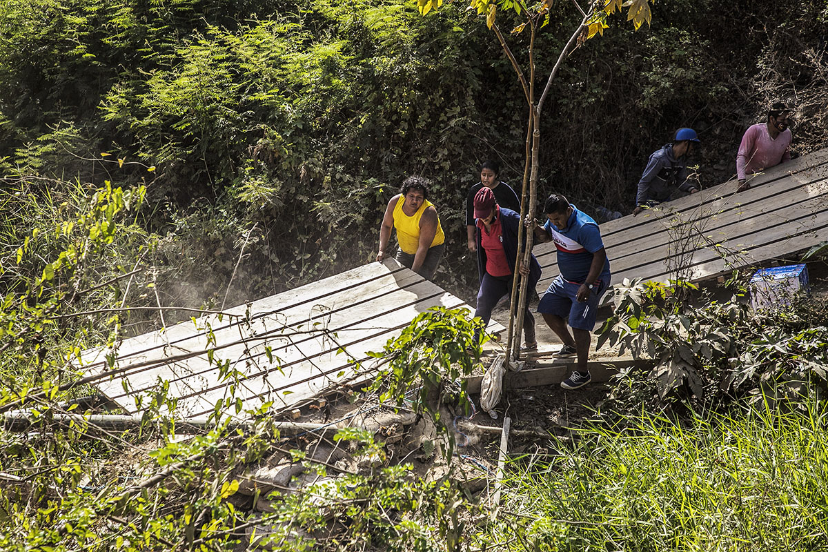 Integrantes de una mafia de "coyotes" retirando el puente ilegal de madera que habían instalado sobre el canal de cemento que divide el Perú y Ecuador. (Foto: Fabiola Granda)